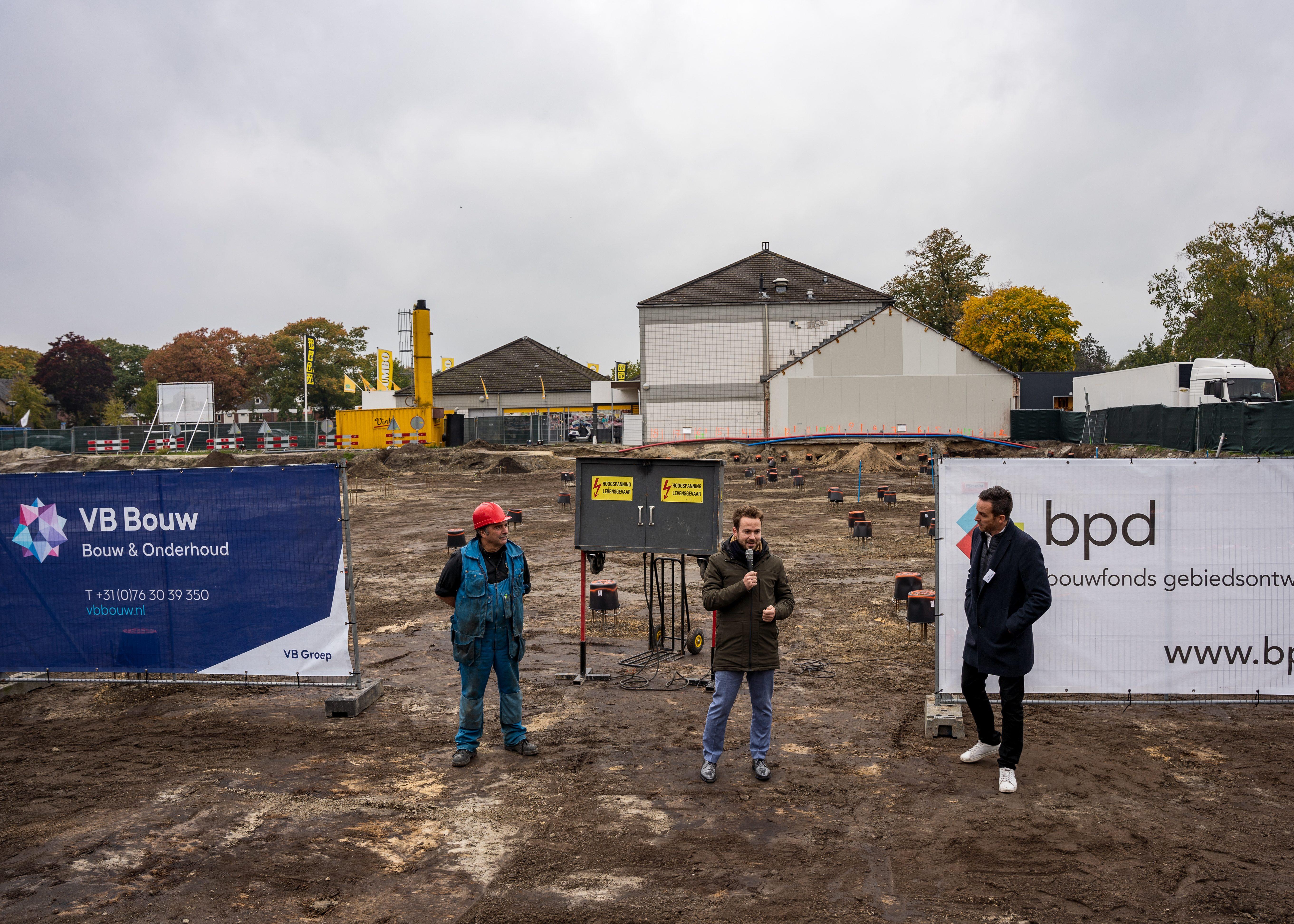 Toespraak op bouwplaats met bouwmedewerker en bouwhekken van VB Bouw en bpd