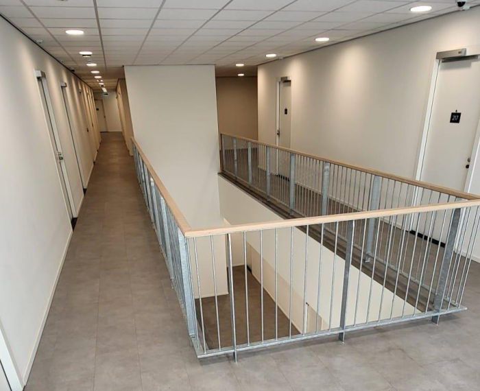 Transformatie voormalig hotel Born – verdieping met stalen balustrade rond vide, hoteldeuren en spots