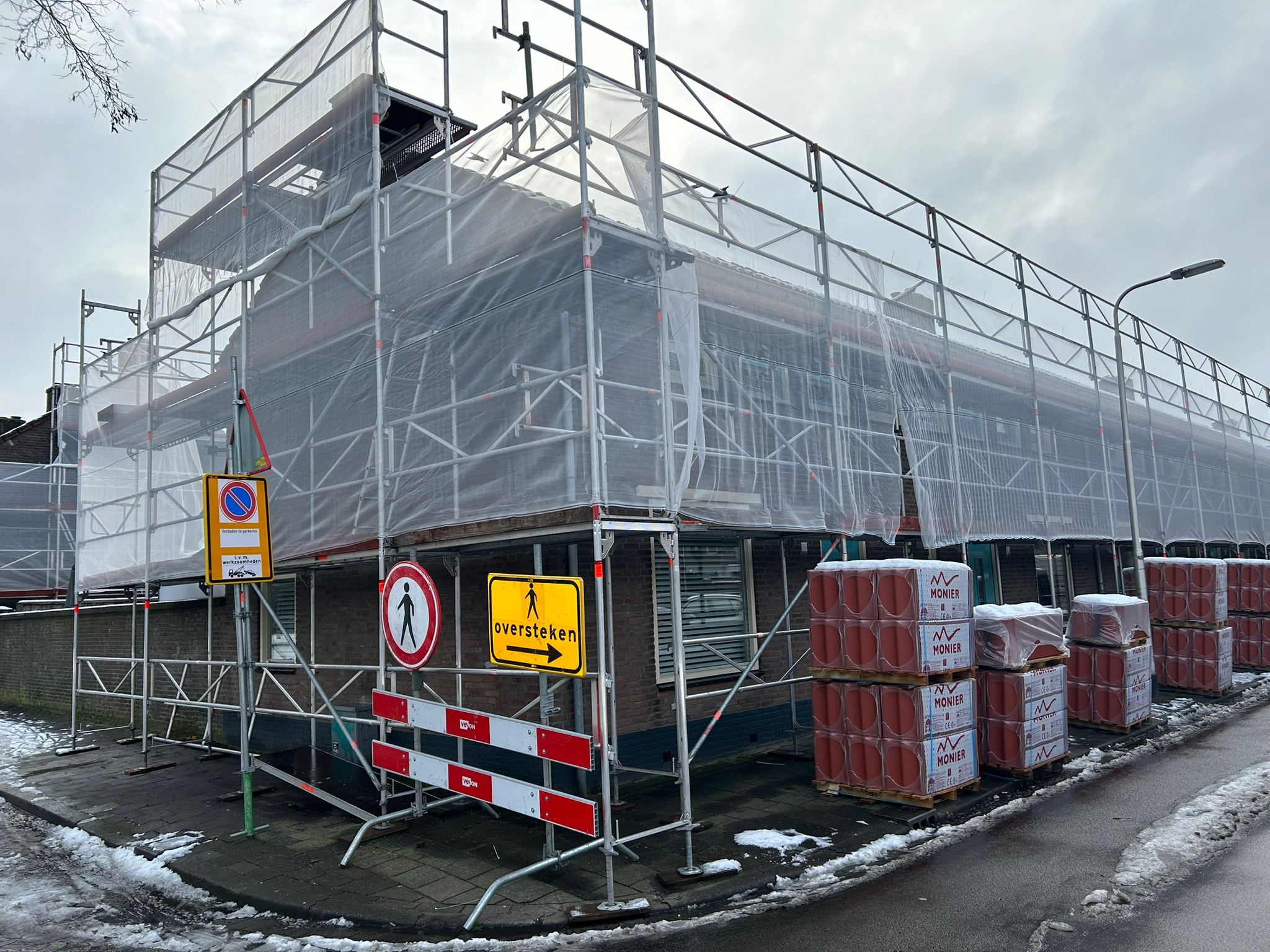 Berkdijk Tilburg groot onderhoud: hoekwoning steigerdoek, verkeersborden, pallets dakpannen, sneeuw.