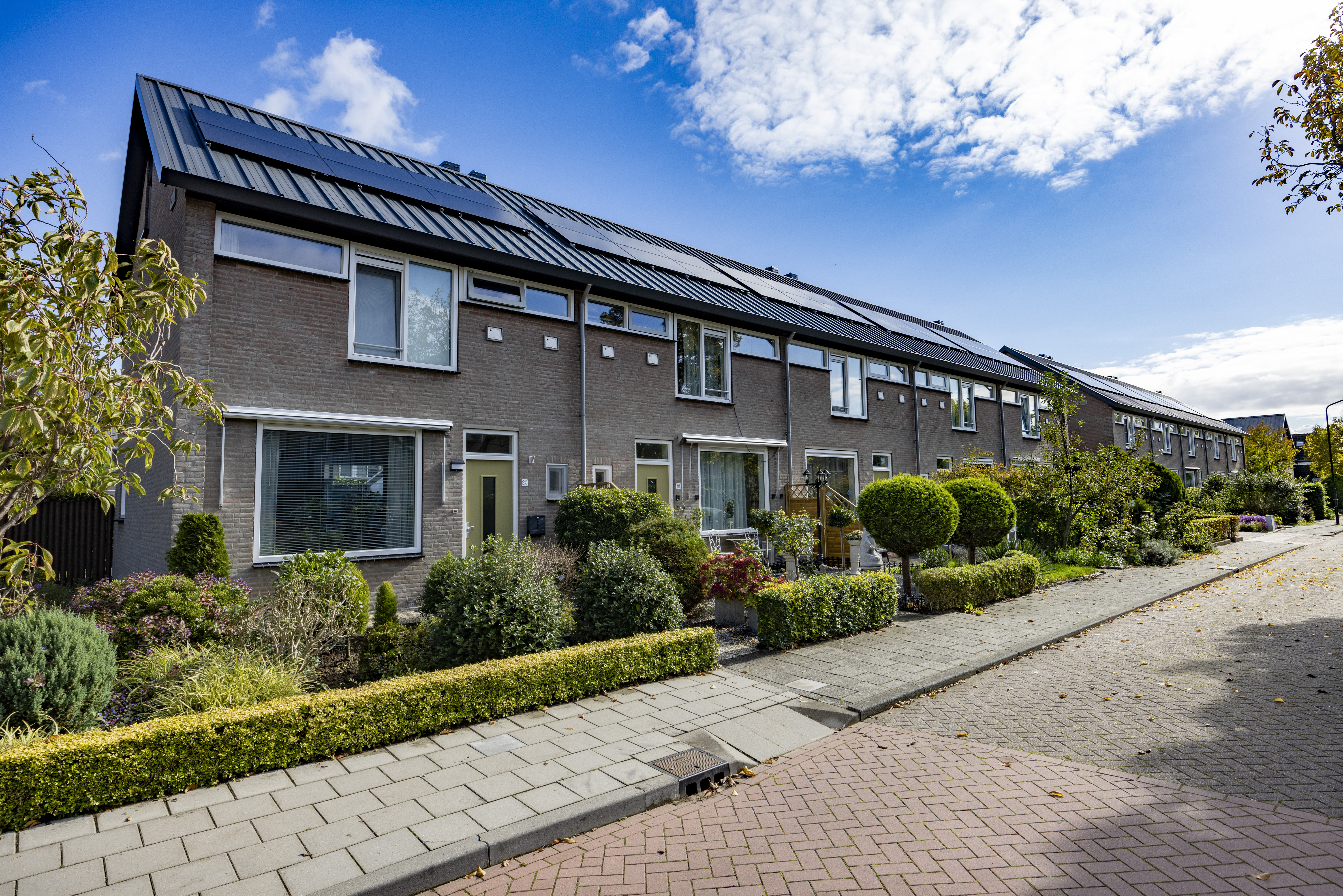 Bloemenwijk Almkerk groot onderhoud: rijhuizen met zonnepanelen, verzorgde tuinen, en hagen, straat.