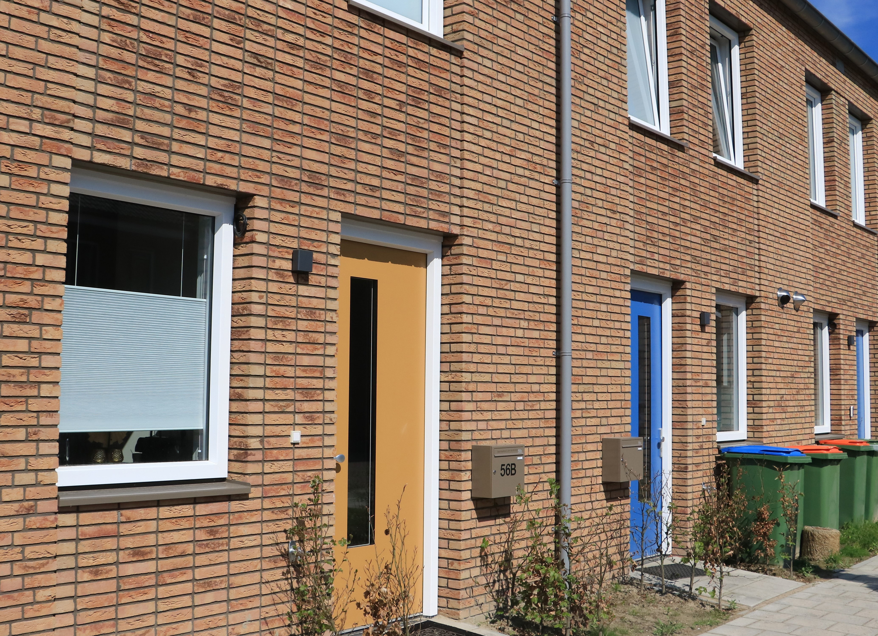 Rijwoningen met bakstenen gevels, kleurrijke voordeuren en witte raamkozijnen