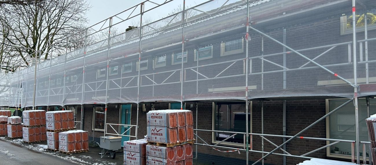 Groot onderhoud Berkdijk Tilburg: rijwoningen in steigerdoek, pallets dakpannen, winterse straat. nu