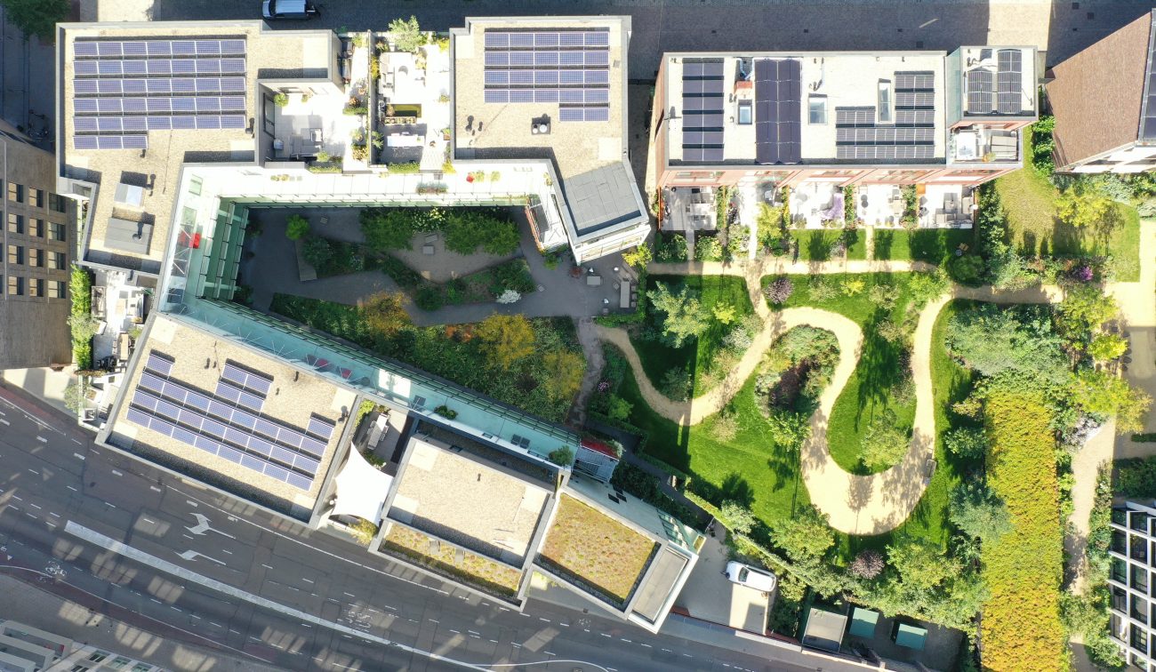 CPO Sphinx Maastricht – verticale luchtfoto van groene binnentuin met slingerpaden, omringd door woonblokken met daken vol zonnepanelen