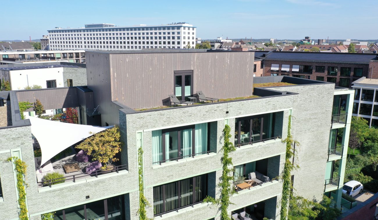 CPO Sphinx Maastricht – detail van appartementen met groene baksteengevel en klimplanten, dakterras met houten opbouw en schaduwdoek