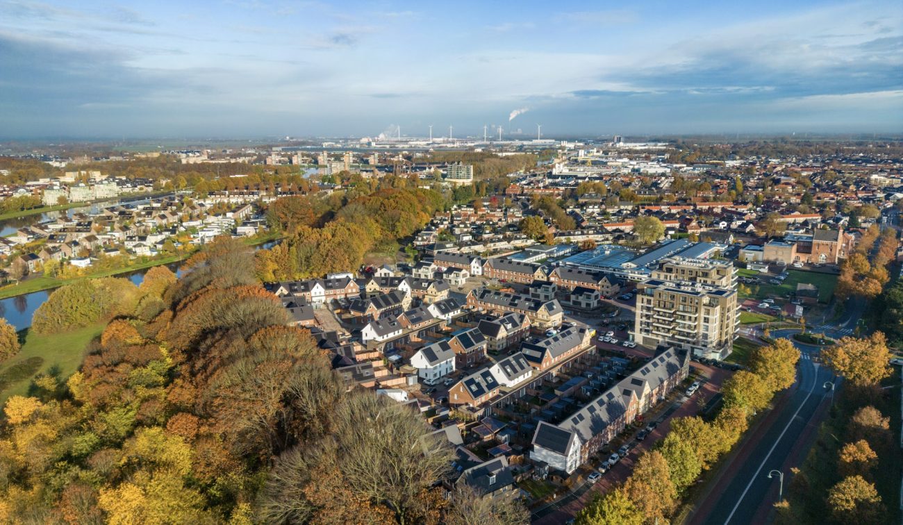 Luchtfoto van het voltooide nieuwbouwproject Wilhelminahaven in Oosterhout, met moderne appartementen en rijwoningen omringd door bomen en infrastructuur.