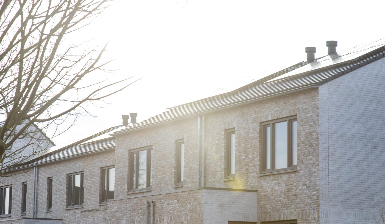 CPO Meerdel Elsloo – detail van lichte bakstenen rijwoningen met bronskleurige kozijnen, hemelwaterafvoeren en zonlicht over het dak