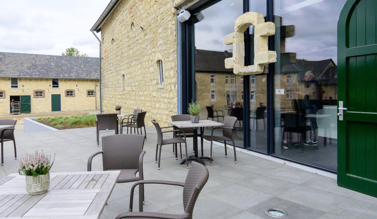 Terras Hoeve Overhuizen met mergelstenen gevel, glazen pui en bistroset.