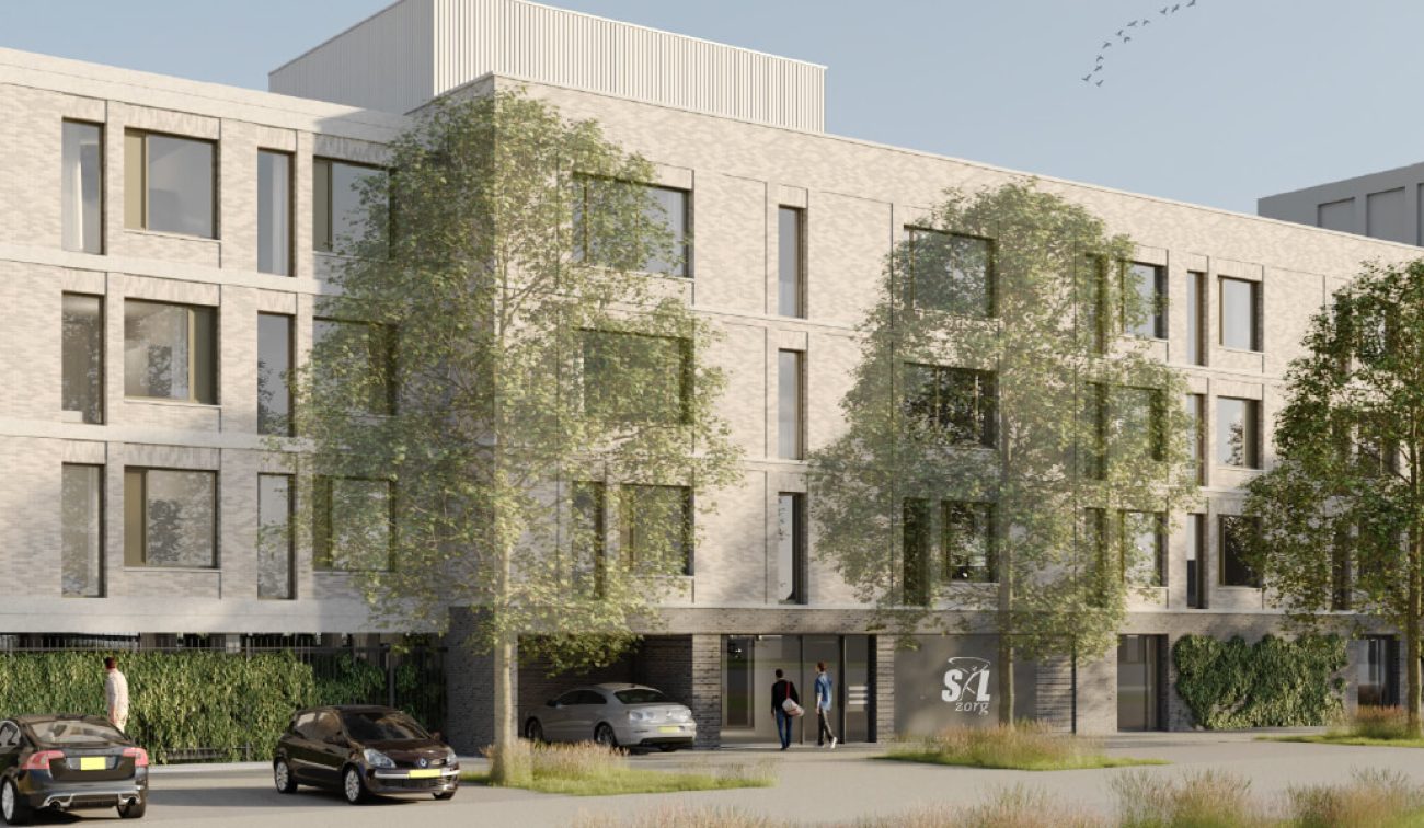 Impressie De Baron Bergen op Zoom: licht bakstenen woongebouw met bomen, entree, parkeren en mensen.