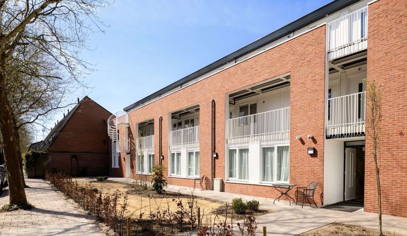 Renovatie en optopping Plataanlaan Baarn: bakstenen woongebouw met balkon, galerij en paden in tuin.