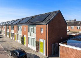 Wandelbos Tilburg verduurzaming: rijwoningen met zonnepanelen, rode baksteen en groene deuren. strak