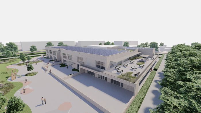 Kernkindcentrum Maastricht-West – impressie van school met groot PV-dak, terrassen en speelplein in groene omgeving