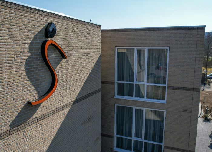 Geveldetail zorgcomplex Valkenheim Valkenburg met oranje S-logo en hoge ramen