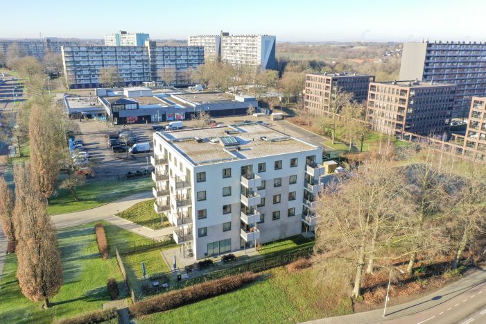Luchtfoto nieuwbouw Noorderkroon Brunssum – vijflaags appartementengebouw met balkons en plat dak, gelegen naast winkelcentrum en hoogbouw in groen stadsdeel