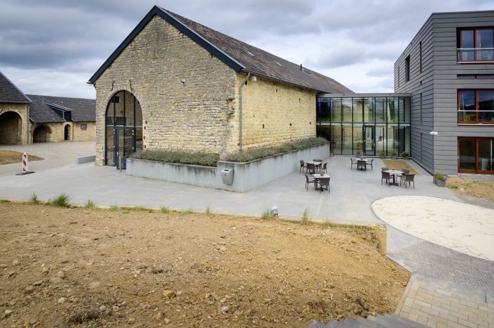 Monumentale schuur Hoeve Overhuizen met mergelstenen gevel en glazen corridor naar nieuwbouw.